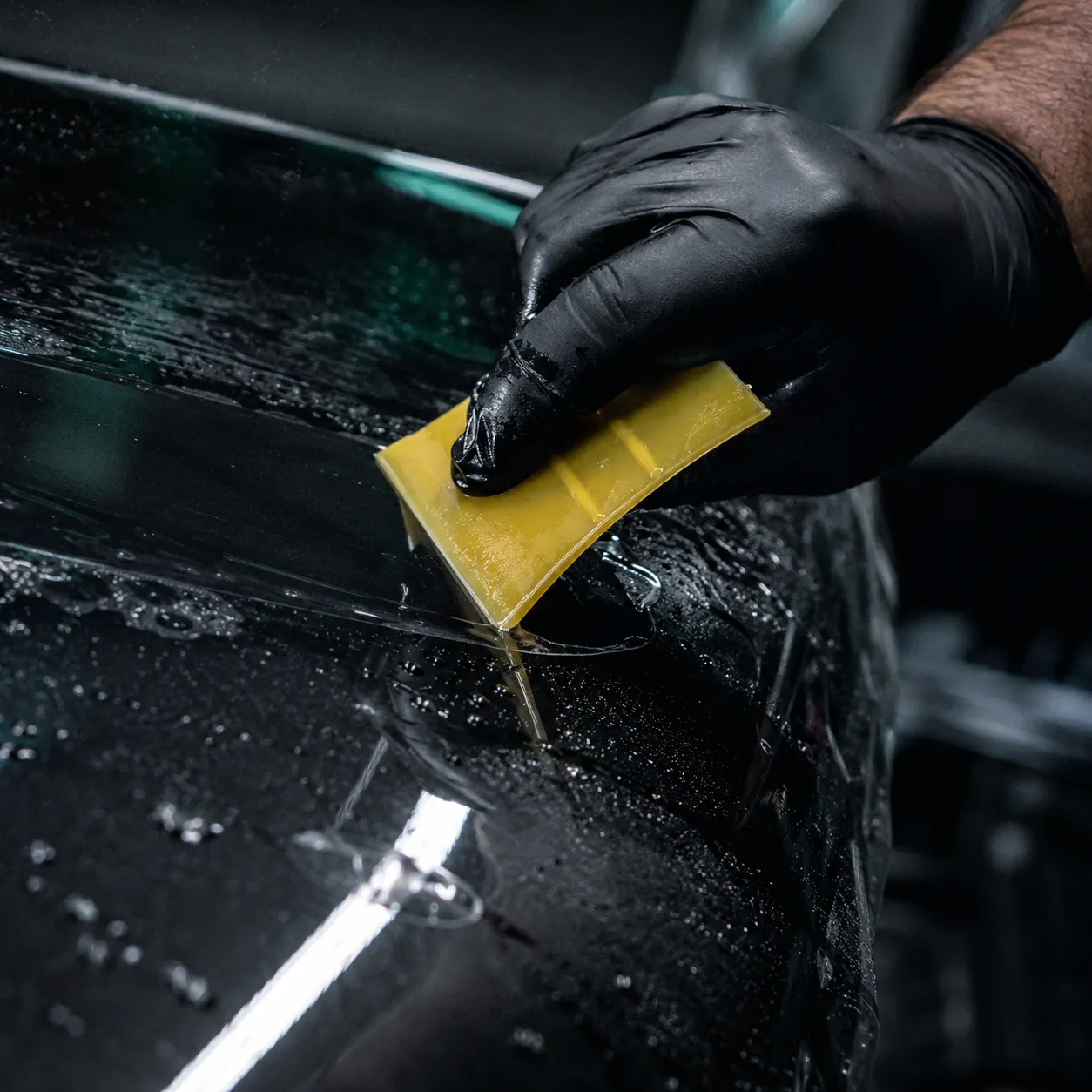 Pose au squeegee d’un film PPF auto-cicatrisant sur carrosserie